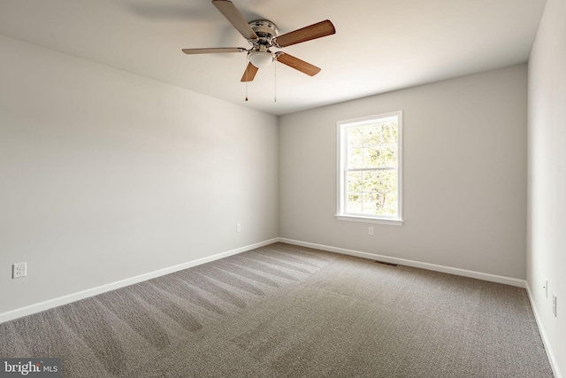 carpeted spare room featuring visible vents, ceiling fan, and baseboards