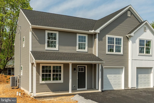 view of front of home featuring driveway, cooling unit, roof with shingles, covered porch, and an attached garage