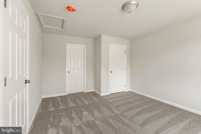 unfurnished bedroom with baseboards, attic access, and carpet flooring