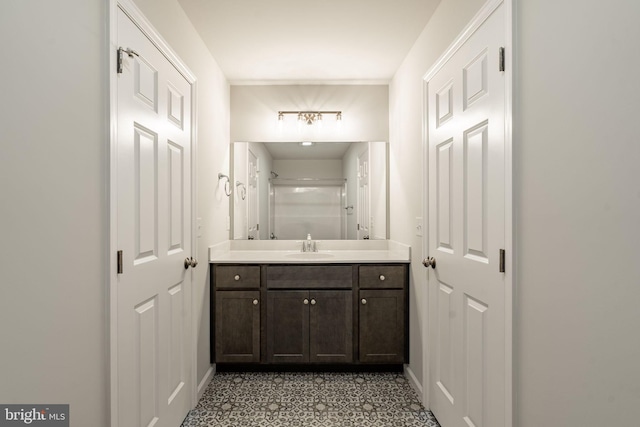 bathroom with a shower, vanity, and baseboards