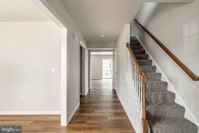 staircase featuring baseboards and wood finished floors