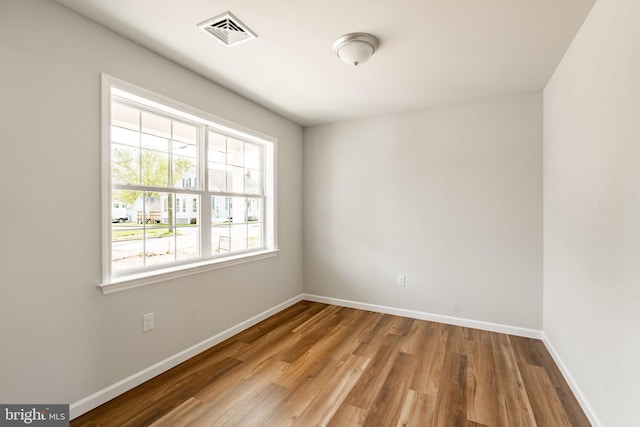 unfurnished room featuring visible vents, wood finished floors, and baseboards
