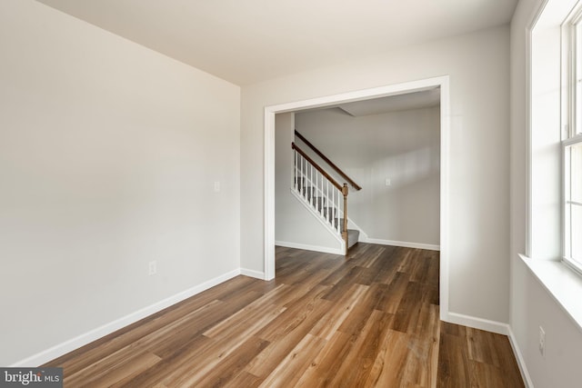 spare room with stairway, wood finished floors, and baseboards