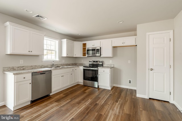 kitchen with stainless steel appliances, light countertops, white cabinetry, visible vents, and dark wood-type flooring