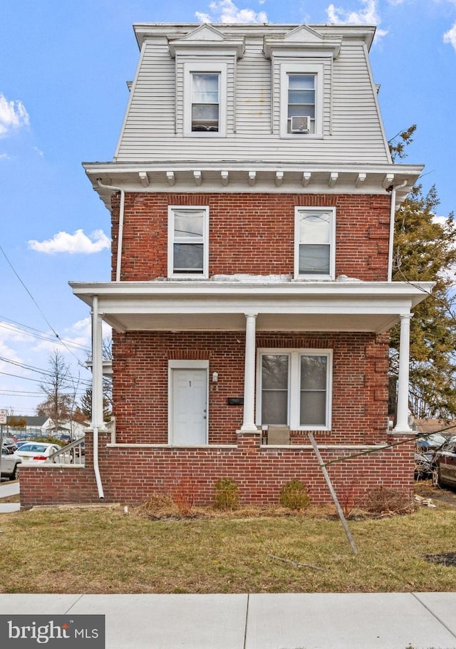 victorian home with brick siding, a porch, and a front lawn