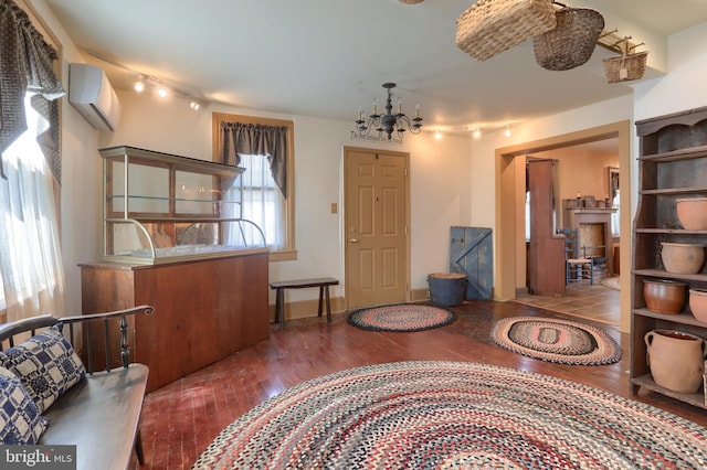 interior space with track lighting, a wall unit AC, wood-type flooring, and a notable chandelier