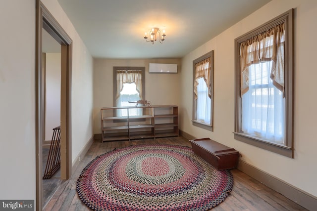 doorway featuring a chandelier, baseboards, a wall mounted AC, and wood finished floors
