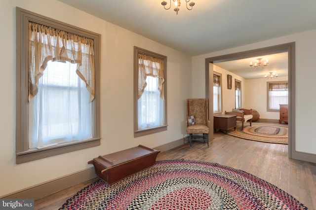interior space featuring baseboards, wood finished floors, and a notable chandelier
