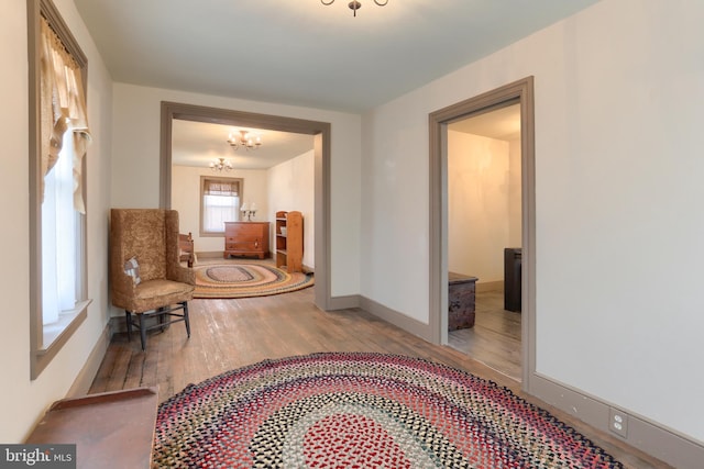 corridor with an inviting chandelier, baseboards, and wood finished floors