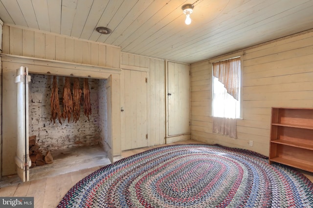 unfurnished bedroom with wooden walls, wood ceiling, and light wood-type flooring