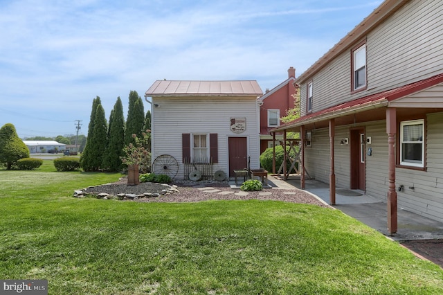 view of front facade with a standing seam roof, metal roof, and a front yard