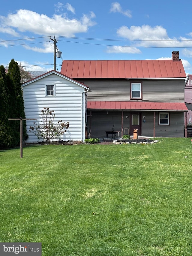 back of property featuring a yard, metal roof, and a standing seam roof