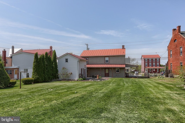 back of house featuring a lawn, a chimney, and metal roof