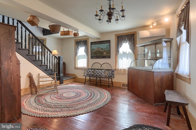 entrance foyer featuring a wall mounted air conditioner, baseboards, a notable chandelier, stairs, and hardwood / wood-style floors