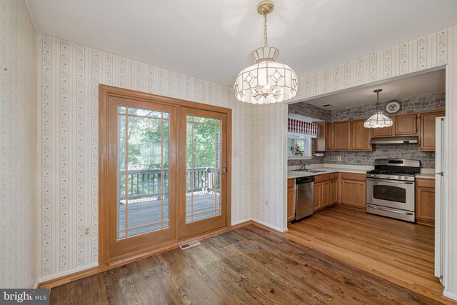 kitchen with visible vents, wood finished floors, under cabinet range hood, a sink, and appliances with stainless steel finishes