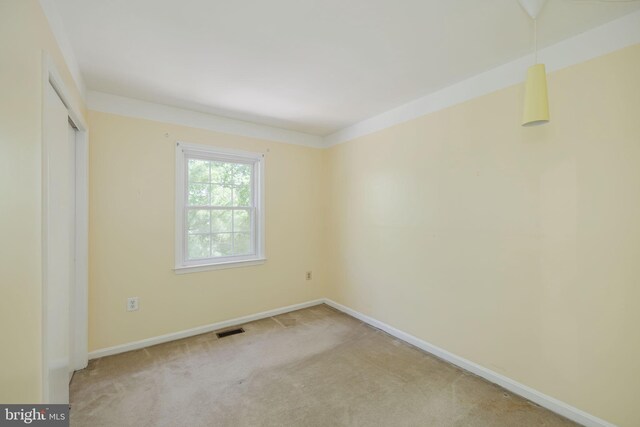 empty room with visible vents, baseboards, and light colored carpet