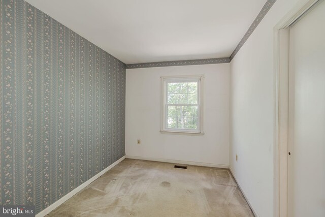carpeted spare room featuring baseboards and visible vents