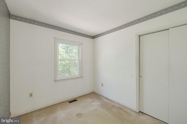unfurnished bedroom with visible vents, baseboards, carpet floors, and a closet
