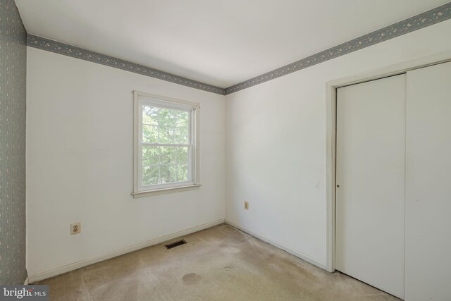 unfurnished bedroom with visible vents, carpet, baseboards, and a closet