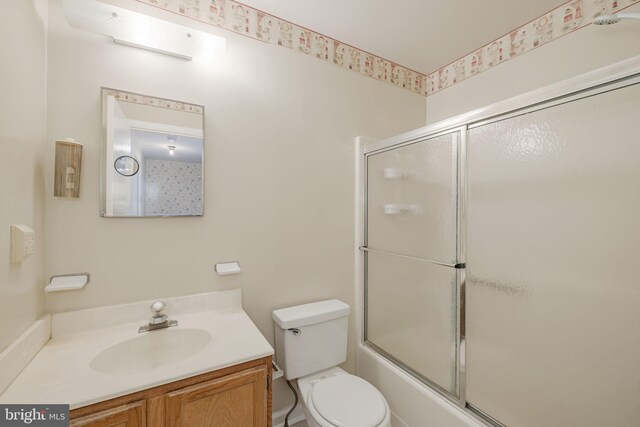 full bath featuring vanity, toilet, and shower / bath combination with glass door