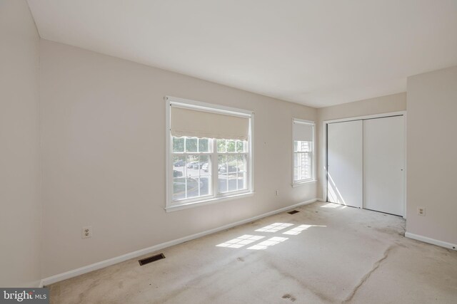 unfurnished bedroom featuring carpet flooring, baseboards, visible vents, and a closet
