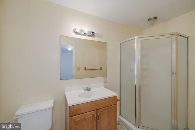 bathroom with vanity, a shower stall, and toilet