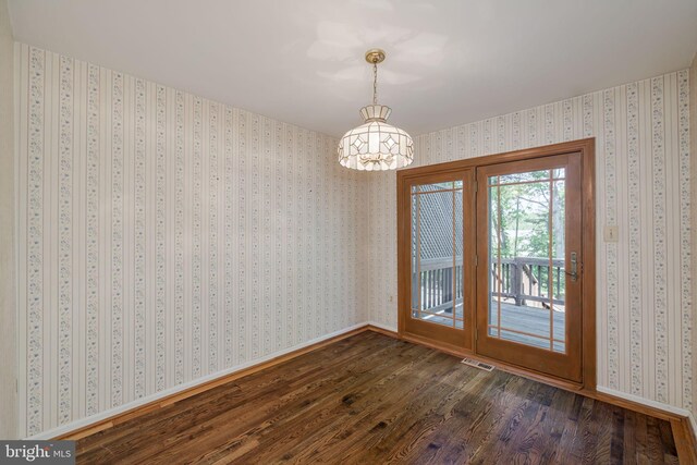 unfurnished dining area with visible vents, baseboards, a notable chandelier, and dark wood-style floors