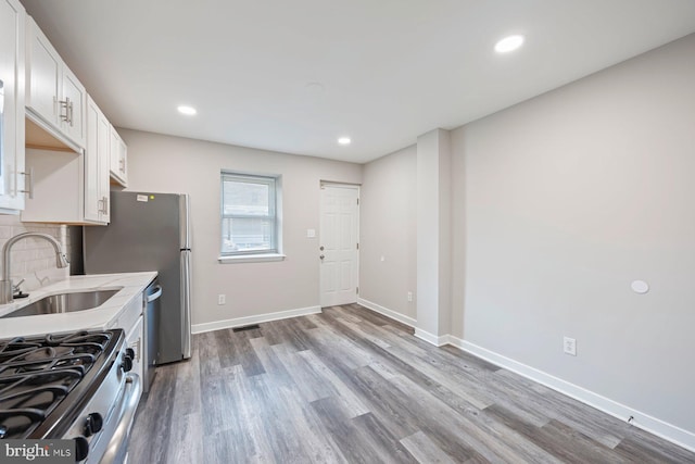 3302 W Belvedere Ave, Baltimore, MD 21215 - kitchen featuring white cabinets, appliances with stainless steel finishes, a sink, light countertops, and wood finished floors