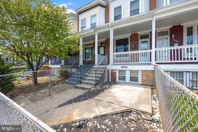 3302 W Belvedere Ave, Baltimore, MD 21215 - property entrance featuring fence, covered porch, and brick siding