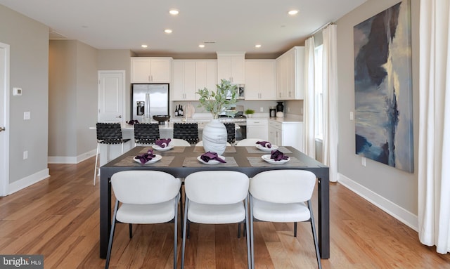kitchen featuring a center island, light wood-type flooring, appliances with stainless steel finishes, and baseboards