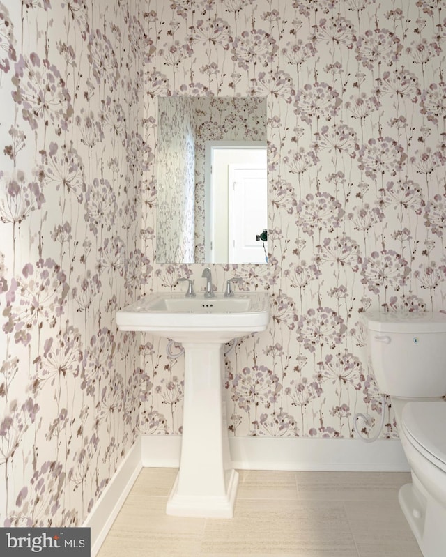 half bath featuring wallpapered walls and toilet