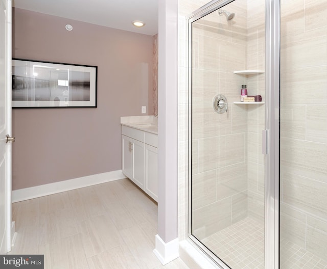 full bathroom with vanity, a shower stall, and baseboards