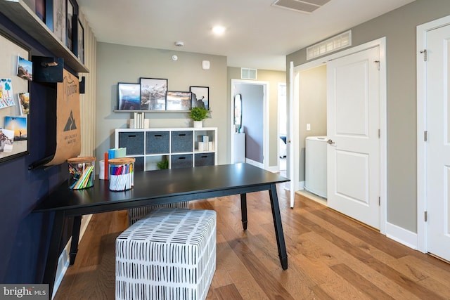 office space with baseboards, visible vents, washer / clothes dryer, and wood finished floors