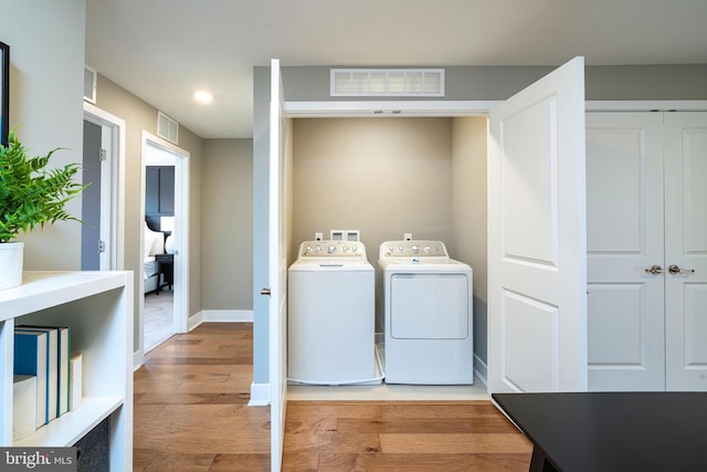 laundry area with separate washer and dryer, laundry area, light wood-style floors, baseboards, and visible vents