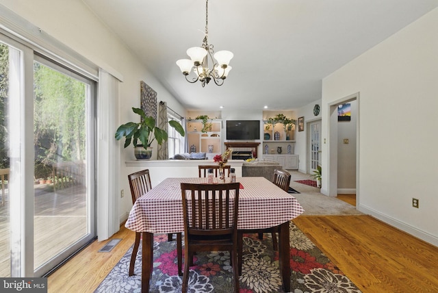 dining space featuring a notable chandelier, visible vents, baseboards, and light wood-style floors