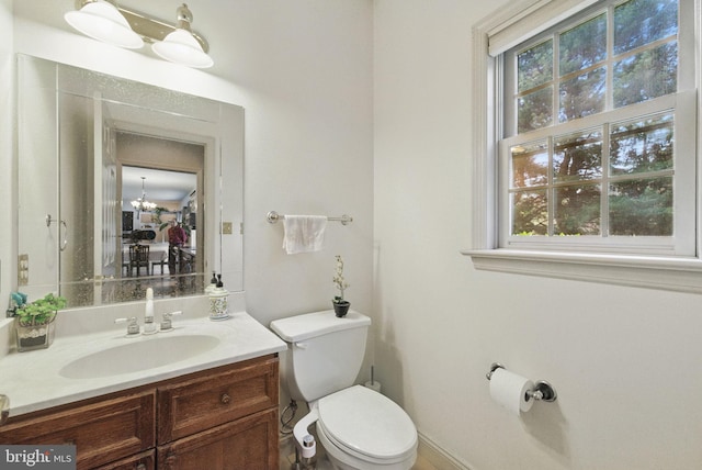 half bath featuring toilet, plenty of natural light, and vanity