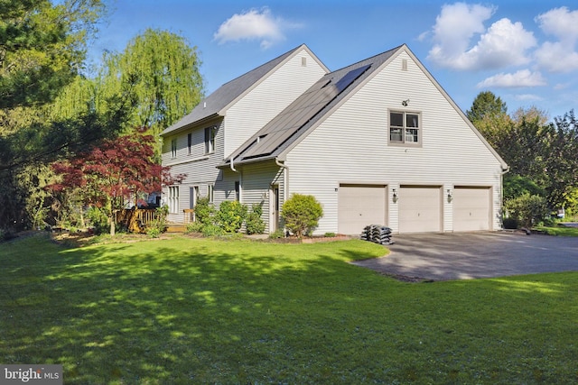 view of side of property with a lawn, an attached garage, solar panels, and aphalt driveway