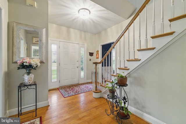 foyer with stairs, baseboards, and wood finished floors