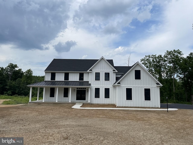 modern farmhouse featuring board and batten siding, a standing seam roof, metal roof, a shingled roof, and covered porch