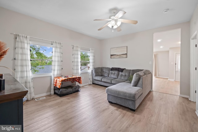 living room featuring visible vents, baseboards, ceiling fan, and light wood-type flooring