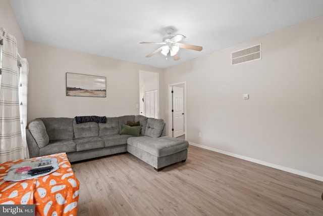 living room featuring baseboards, a ceiling fan, light wood finished floors, and visible vents