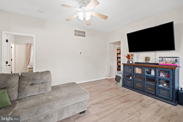 living area with baseboards, ceiling fan, visible vents, and wood finished floors