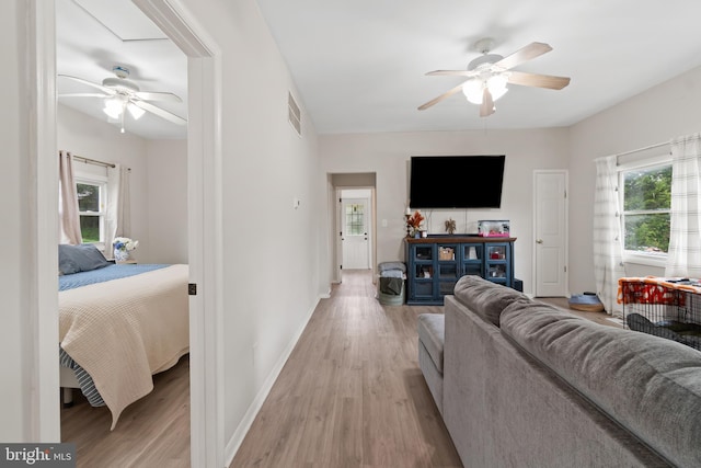 living room featuring light wood-type flooring, baseboards, and ceiling fan