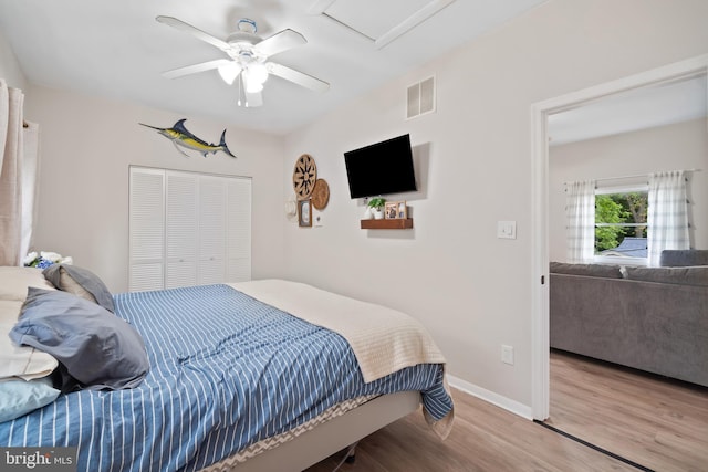 bedroom with visible vents, a closet, wood finished floors, attic access, and ceiling fan