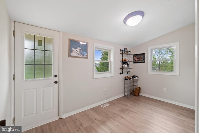 doorway to outside featuring baseboards, a wealth of natural light, lofted ceiling, and light wood-style floors