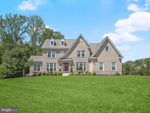 colonial inspired home featuring brick siding and a front yard