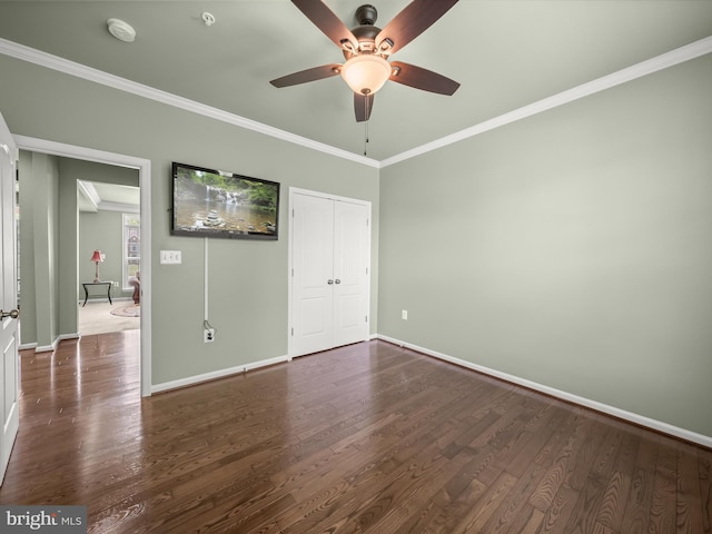 unfurnished bedroom featuring baseboards, wood finished floors, ornamental molding, a closet, and ceiling fan