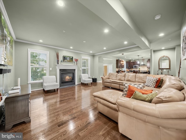living room with dark wood-style flooring, a glass covered fireplace, recessed lighting, baseboards, and ornamental molding