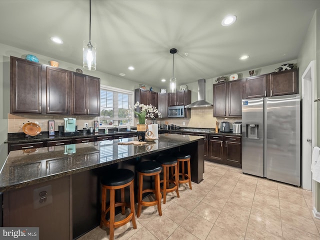 kitchen featuring wall chimney exhaust hood, appliances with stainless steel finishes, tasteful backsplash, dark brown cabinetry, and a center island