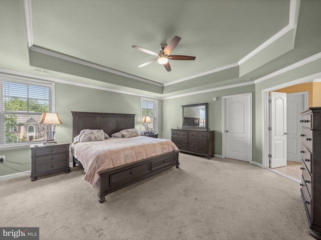 bedroom with a raised ceiling, baseboards, light colored carpet, ornamental molding, and ceiling fan